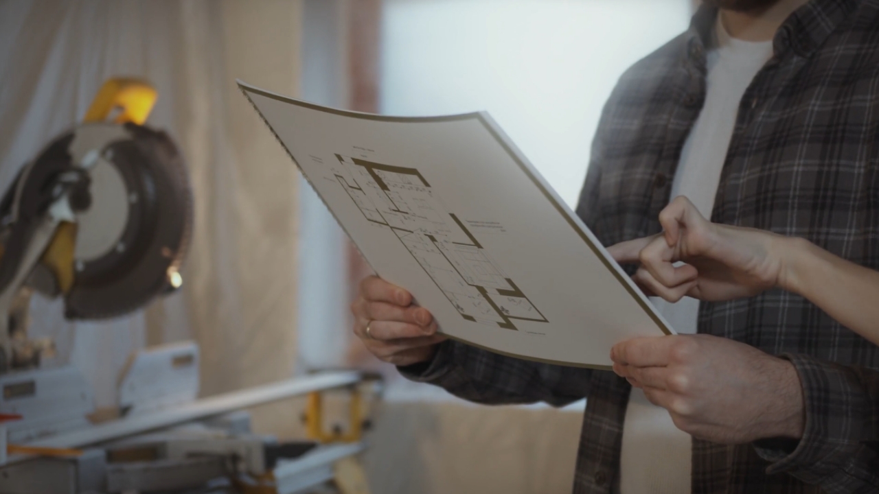 A homeowner reviews renovation plans beside construction tools.