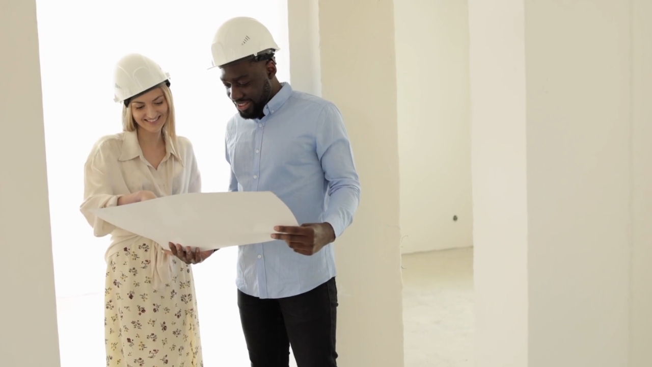 Two renovation professionals review project plans inside an unfinished home.