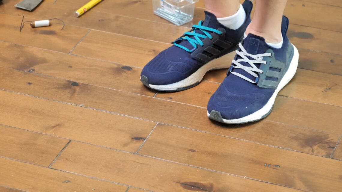 A person tests a hardwood floor for squeaks by stepping on loose boards.