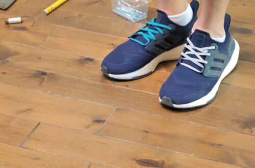A person tests a hardwood floor for squeaks by stepping on loose boards.