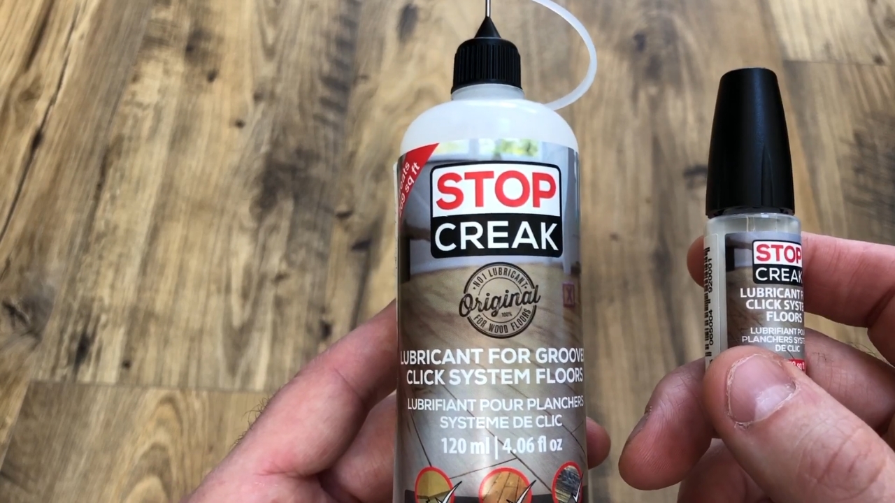 Two Stop Creak floor lubricants held above a wood floor.