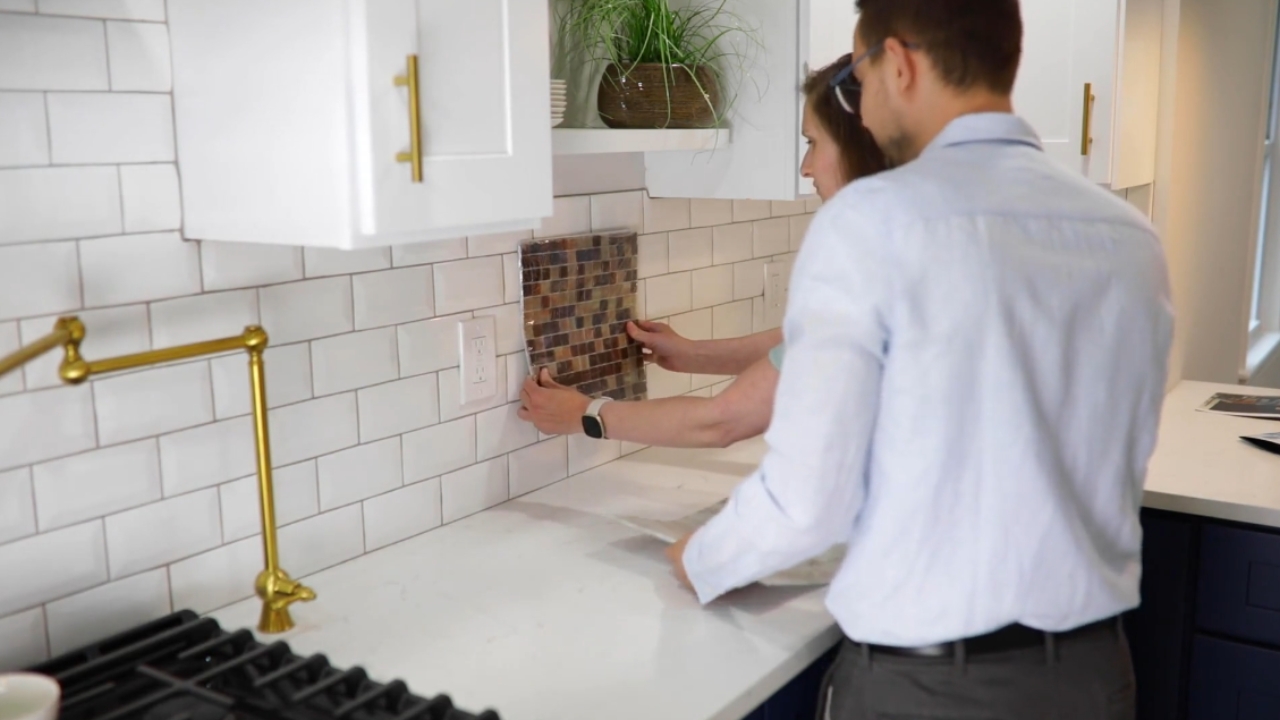 Two homeowners compare tile samples for a kitchen renovation.