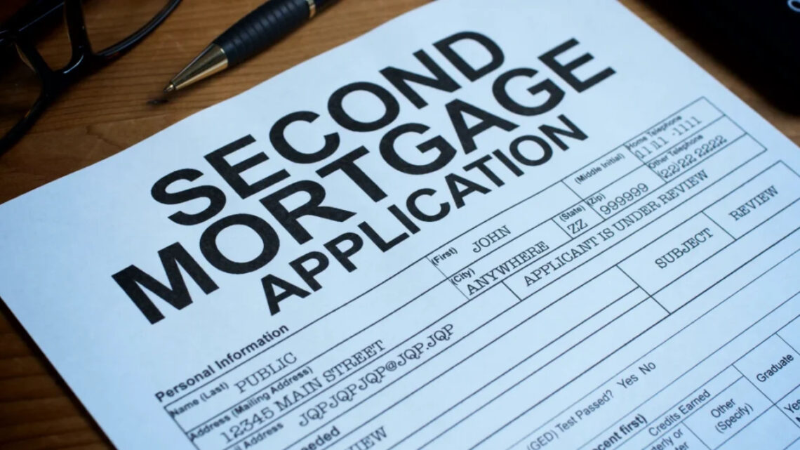 A second mortgage application form sits on a wooden desk beside a pen and glasses.