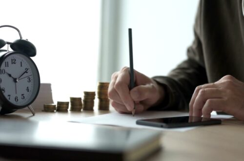 A homeowner calculates renovation costs beside a clock and stacks of coins.