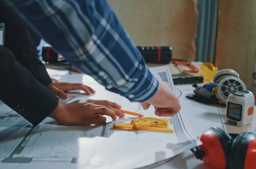 Two people review renovation plans and measurements at a construction site.