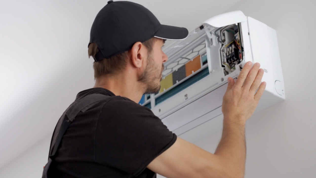 Technician checks an open wall-mounted air conditioner.