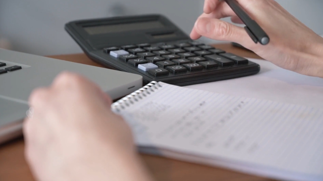 Homeowner calculates repair costs beside a laptop and notebook.