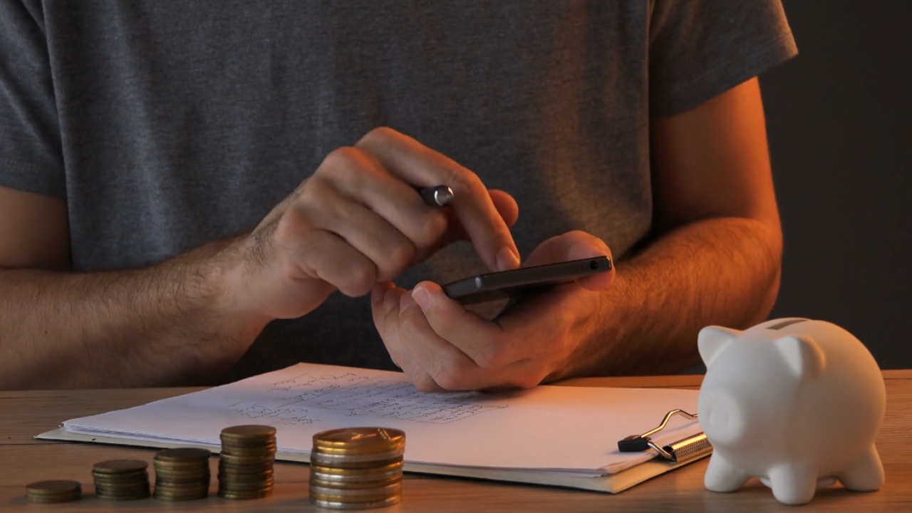 Homeowner reviews finances beside coins and a piggy bank.