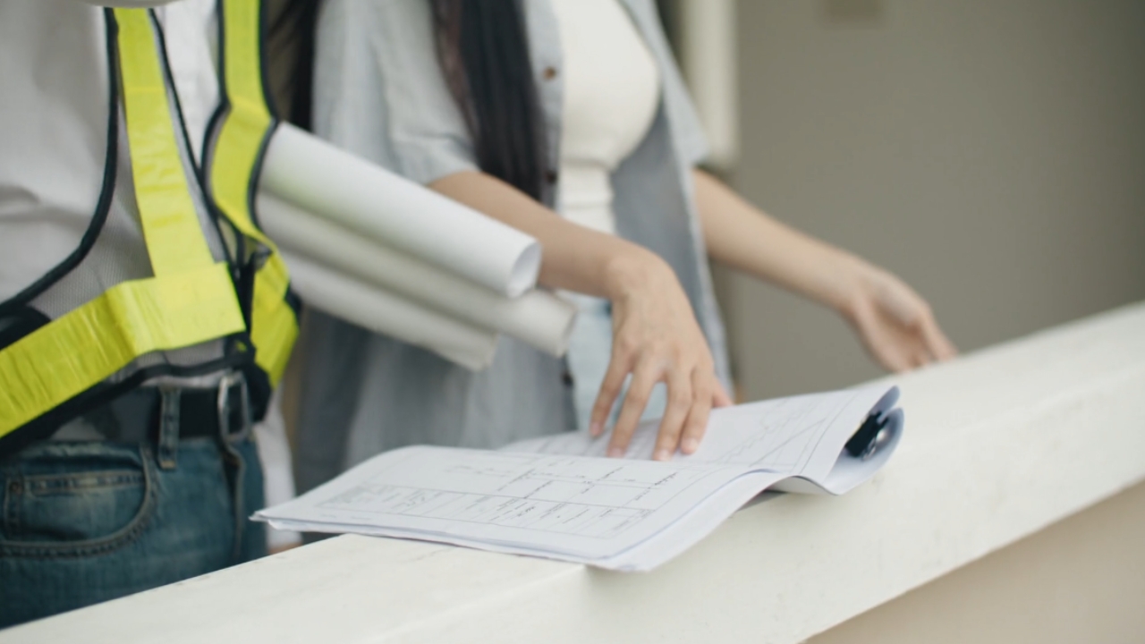 Contractor and homeowner review renovation plans at a worksite.